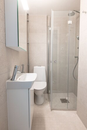 A modern bathroom with a glass-enclosed shower, a white sink, and a toilet. - 2ndhomes Modern Studio close to the Sea (Helsinki)