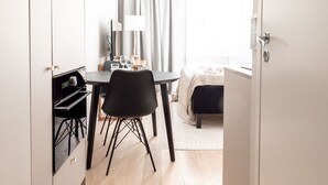 A modern hotel room with a wooden floor, a bed with a white headboard, a small table with a lamp, and a chair. - 2ndhomes Modern Studio close to the Sea (Helsinki)