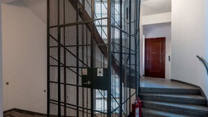 A staircase with a metal safety enclosure, a fire extinguisher, and a red door at the top. - 2ndhomes Modern Studio close to the Sea (Helsinki)