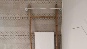 Un baño con un toallero de bambú que sostiene dos toallas blancas.