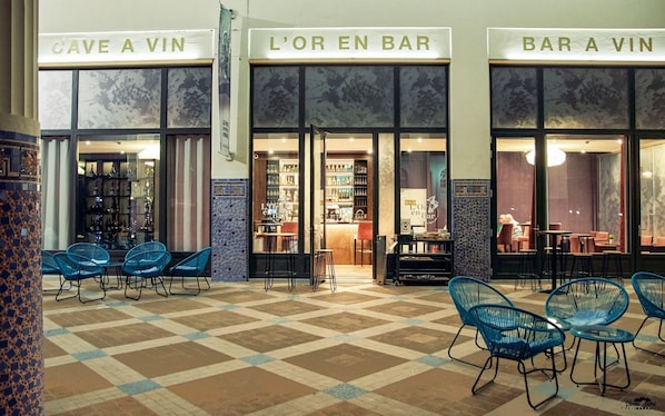 A bar with a checkered floor and blue chairs, and signs reading "CAVE A VIN" and "BAR A VIN".