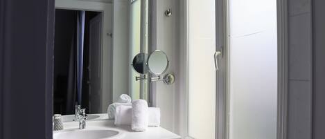 Un baño con un lavamanos blanco, dos espejos y un perchero para toallas.