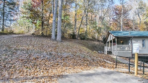 A cabin with a porch, surrounded by trees and fallen leaves. - Cozy Mtn. Getaway in South Asheville (Asheville)