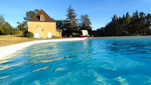 Ein Schwimmbad mit klarem, blauem Wasser, umgeben von einem Haus und Bäumen.