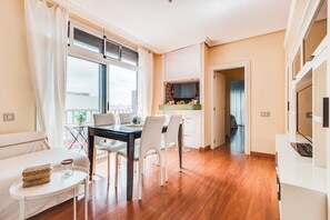 Ein modernes Wohnzimmer mit Essbereich, einer Küche und einem Balkon.