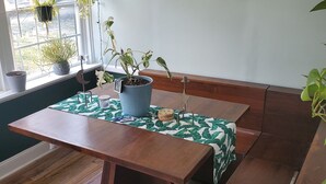 A dining area with a wooden table and bench, potted plants, and a wall clock. - Short Walk to Churchill Downs! (Louisville)