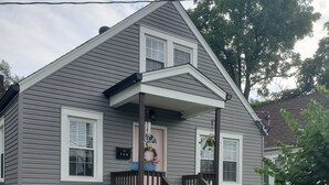 A two-story house with a front porch, a staircase, and a front yard with flowers and plants. - Short Walk to Churchill Downs! (Louisville)