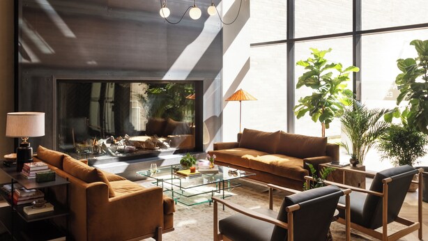 Una sala de estar moderna con chimenea, ventanas amplias y diferentes disposiciones de asientos.