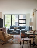 A modern living room with a sofa, coffee table, chairs, and a TV.