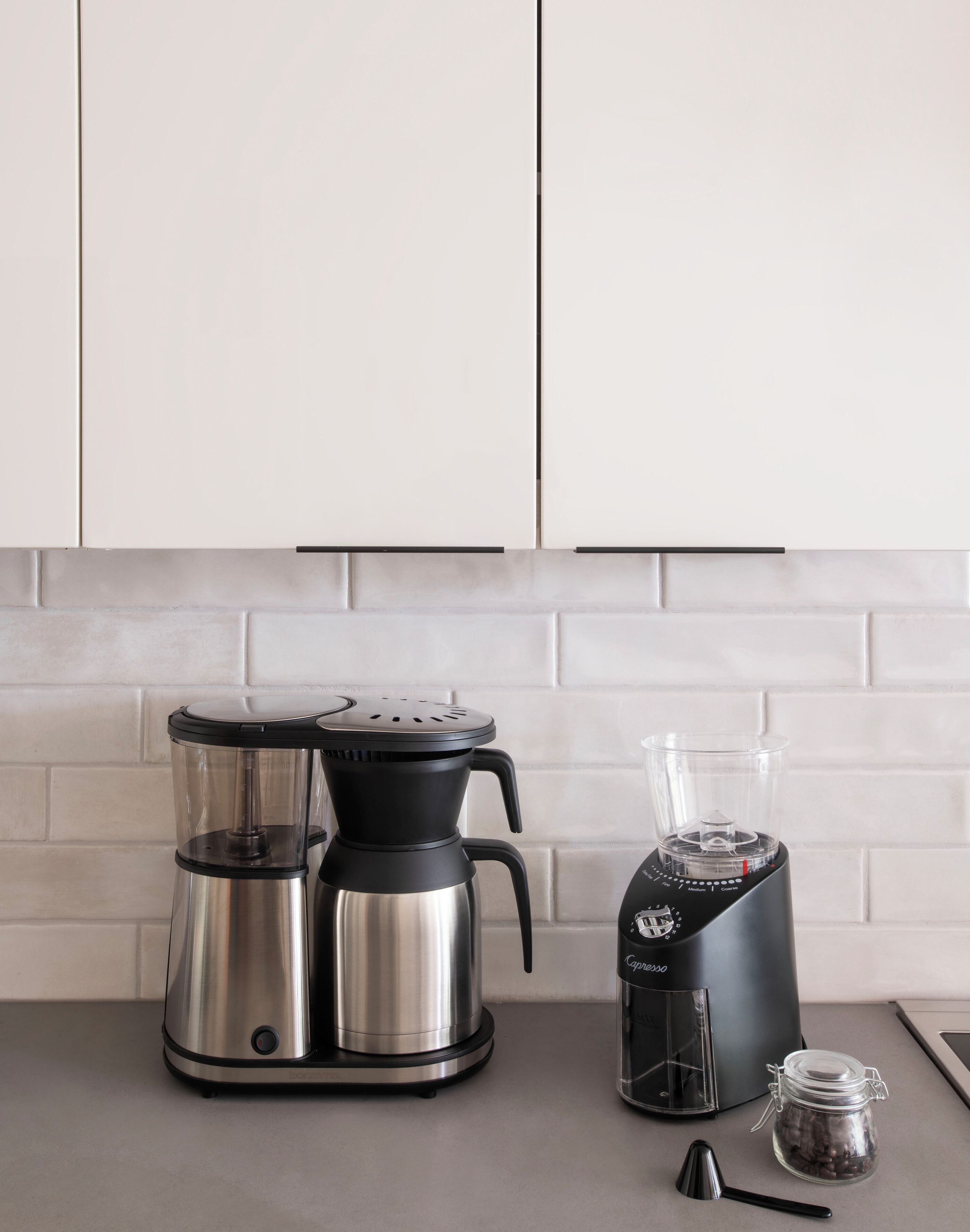 Una cocina con cafetera, licuadora y un tarro de granos de café.