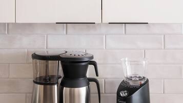 Una cocina con cafetera, licuadora y un tarro de granos de café.