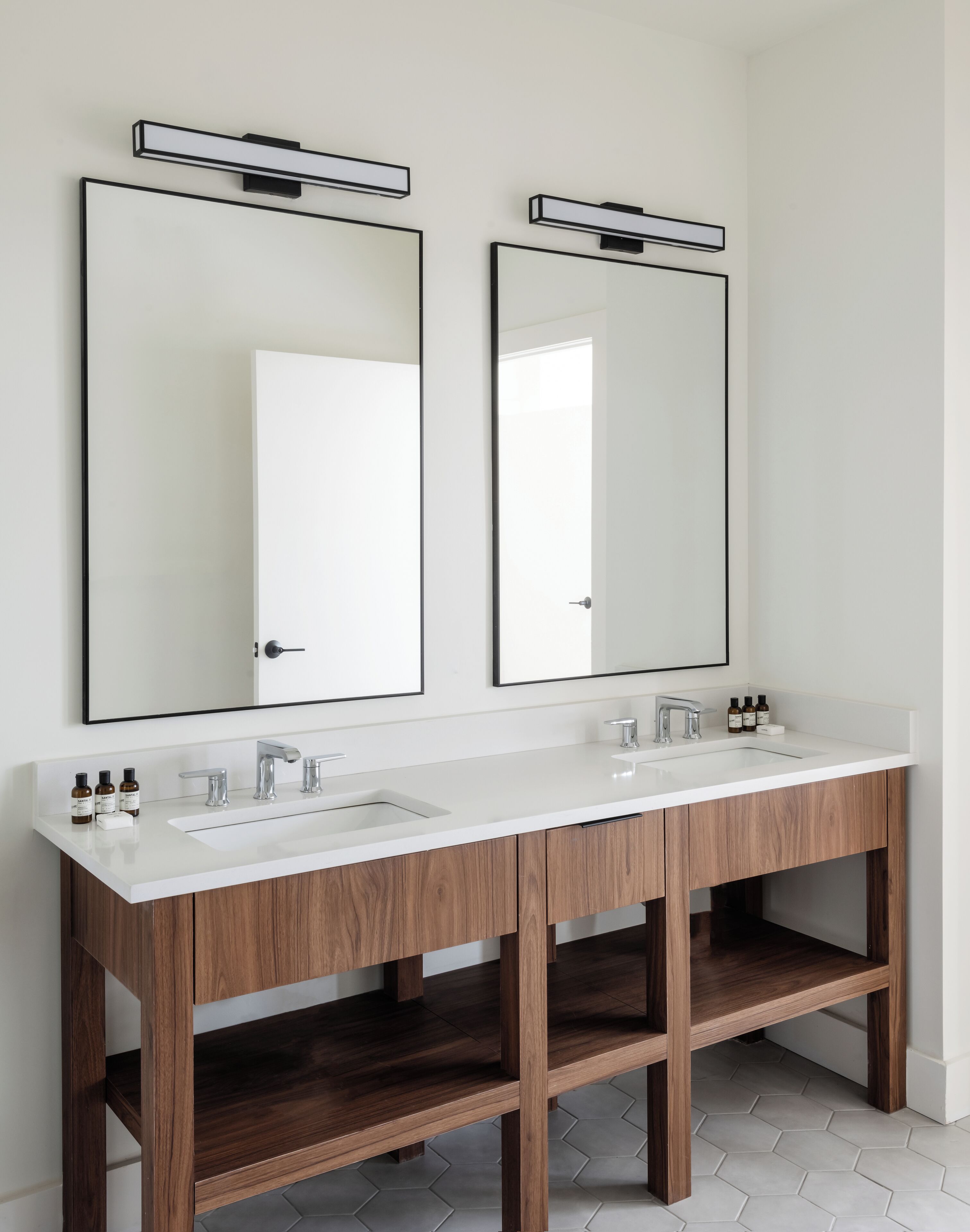 A modern bathroom with two sinks, wooden cabinets, and large mirrors.
