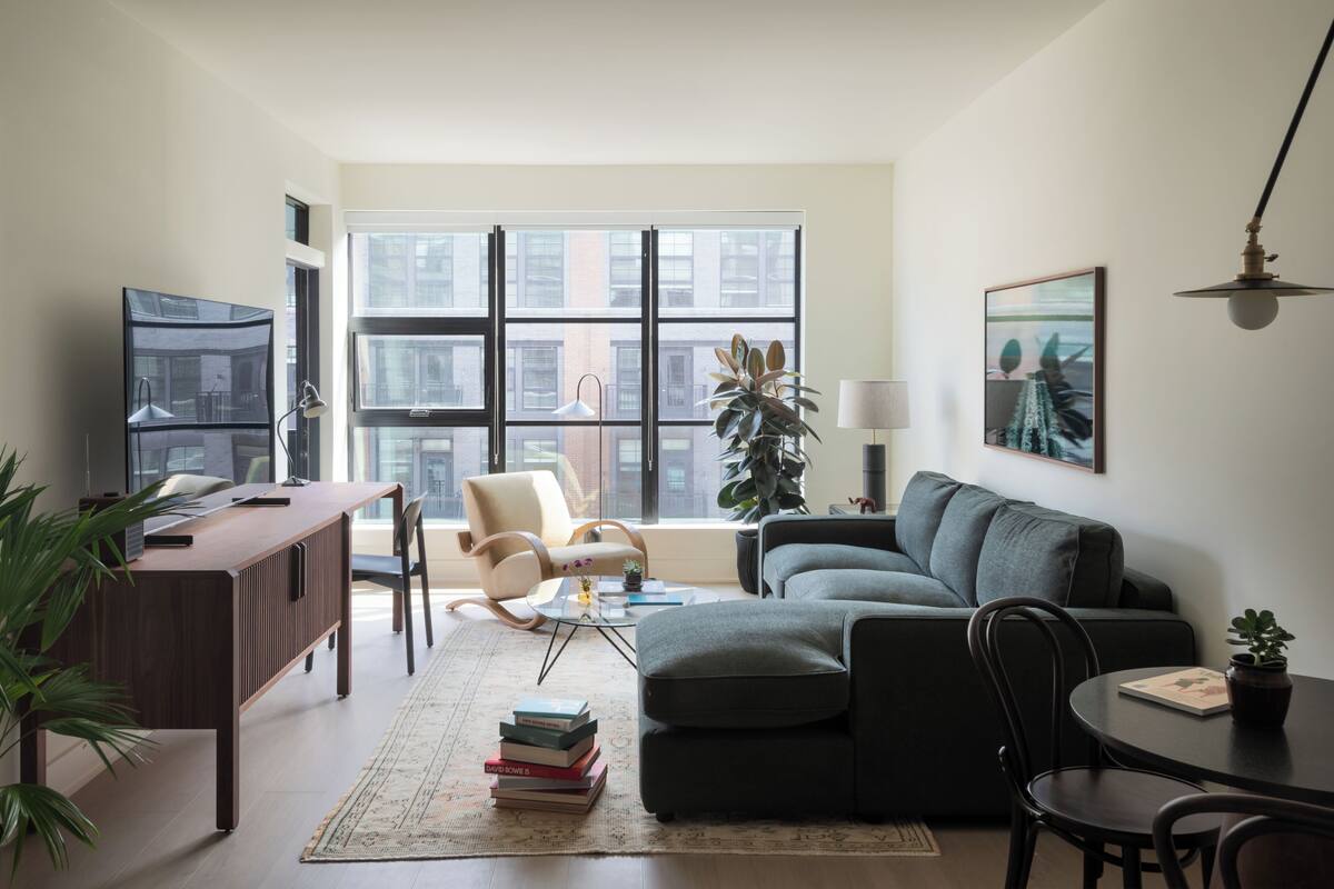 A modern living room with a sofa, armchair, and a dining table.