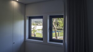 Ein Zimmer mit zwei Fenstern, einer Tür und Blick auf eine grüne Landschaft.