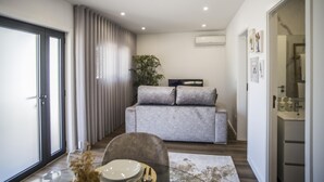 Ein modernes Wohnzimmer mit einem grauen Sofa, einem Glastisch und einer Pflanze.