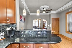 Enjoy meals in this kitchen with a curved countertop, pendant lights, and a dining area with a wooden table.