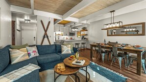 Ein modernes Wohnzimmer mit einem blauen Sofa, einem Holztisch und einem Essbereich inklusive Holztisch und Stühlen.