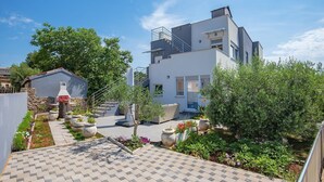Et moderne hus med fliseterrasse, udendørs møbler og grillområde.