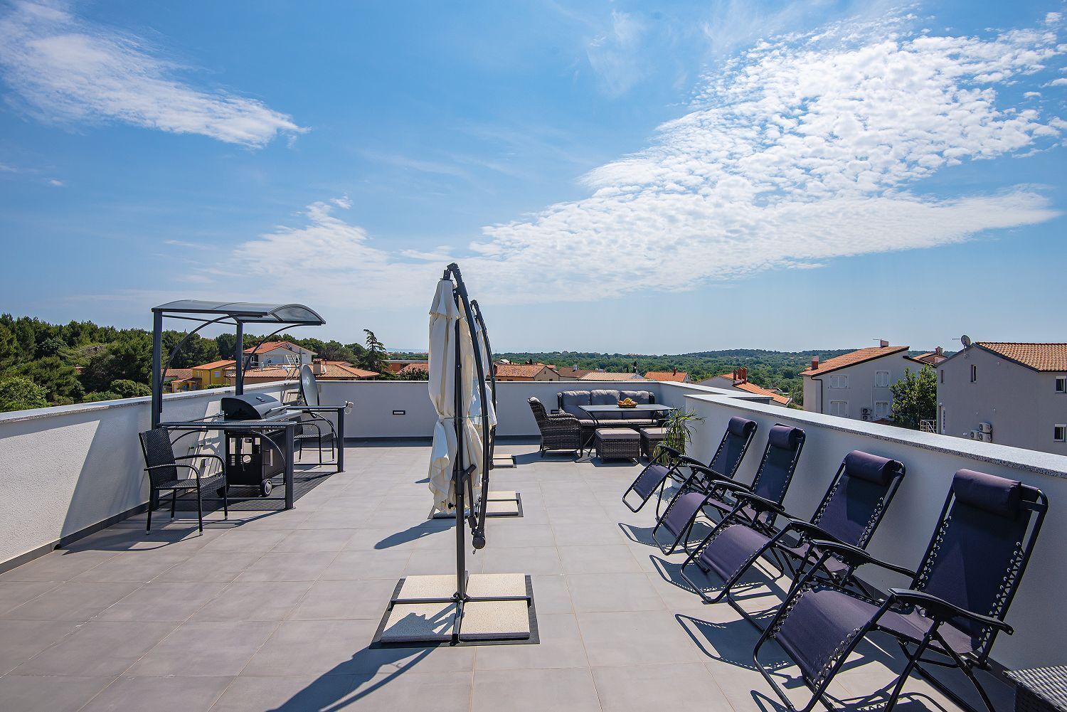 Une terrasse sur le toit, aménagée avec du mobilier d’extérieur, une pergola et offrant une vue sur les environs.