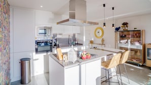 A modern kitchen with white cabinetry, a central island with bar stools, a stainless steel range hood, and a microwave. - Exclusive, quiet urbanization Oasis 325 (AN)