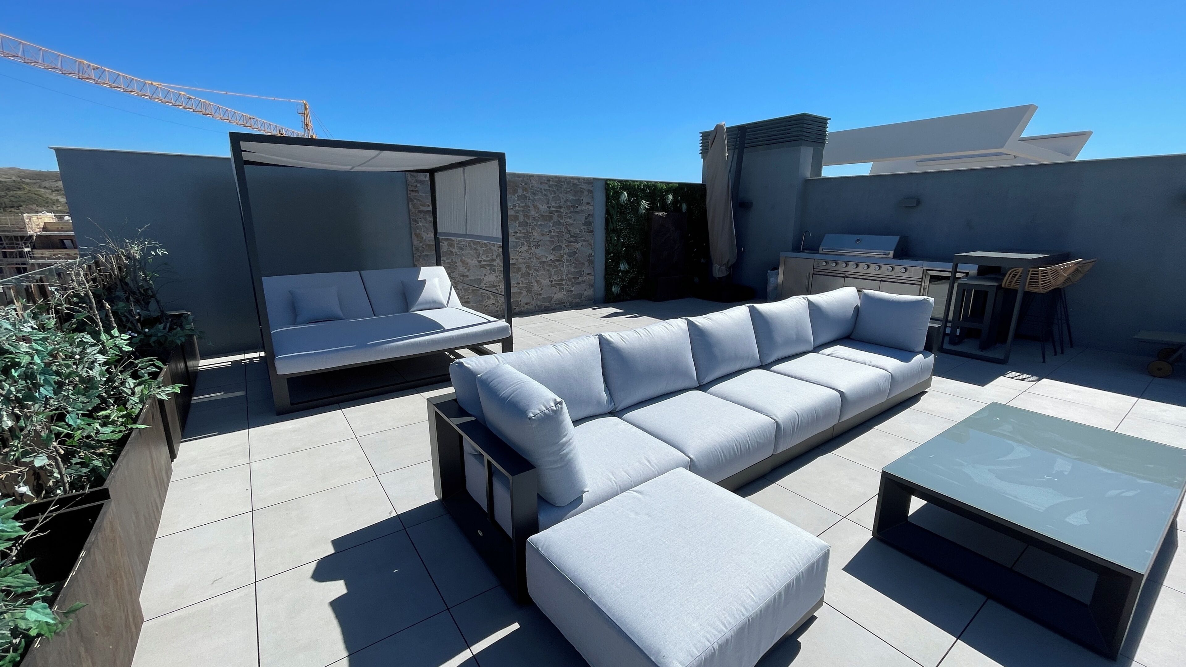 A rooftop patio with a sofa, a small table, and a grill area.