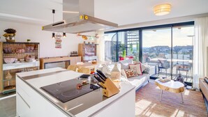 A modern kitchen with a large island, a dining area with a view, and a cozy seating area with a sofa and a small round table. - Exclusive, quiet urbanization Oasis 325 (AN)