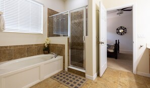 Bathroom features a large bathtub, glass-enclosed shower, and toilet.
