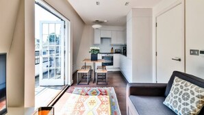 Un apartamento moderno con comedor, kitchenette y una zona de estar acogedora con sofá y alfombra estampada.