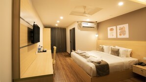 A modern hotel room with a large bed, a flat-screen TV mounted on the wall, an air conditioning unit, and a ceiling fan. - ADDRESS7 Hotel Kalamassery (Kanayannur)