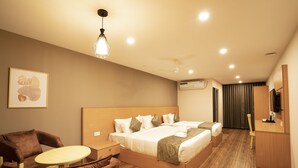 A hotel room with a large bed, a desk, a chair, and a ceiling fan. - ADDRESS7 Hotel Kalamassery (Kanayannur)