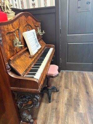 A grand piano with sheet music, a red cushion, and ornate carvings.