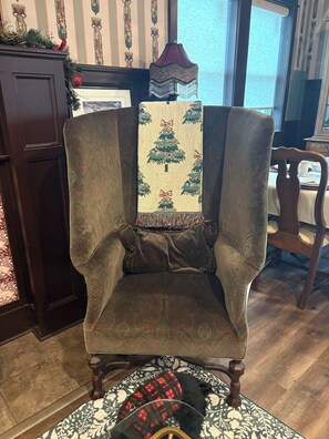 A chair with a patterned cushion, a decorative wall hanging, and a wooden floor.