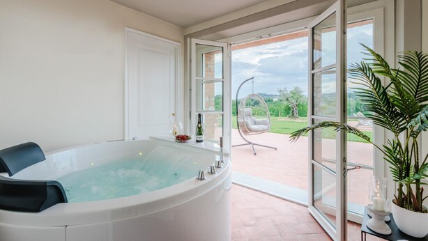 A modern bathroom with a large bathtub, a glass shower enclosure, and a view of the outdoors. - Villa Flora in Montecarlo (Montecarlo)