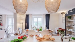 A dining area with a white table set for a meal, surrounded by chairs, a chandelier, and a view of the outdoors. - Villa Flora in Montecarlo (Montecarlo)
