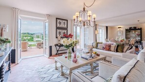 A spacious living room with a large window, a chandelier, and a dining area with a view of the outdoors. - Villa Flora in Montecarlo (Montecarlo)