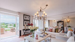 A spacious living room with a large window, a chandelier, and a view of the outdoors. - Villa Flora in Montecarlo (Montecarlo)