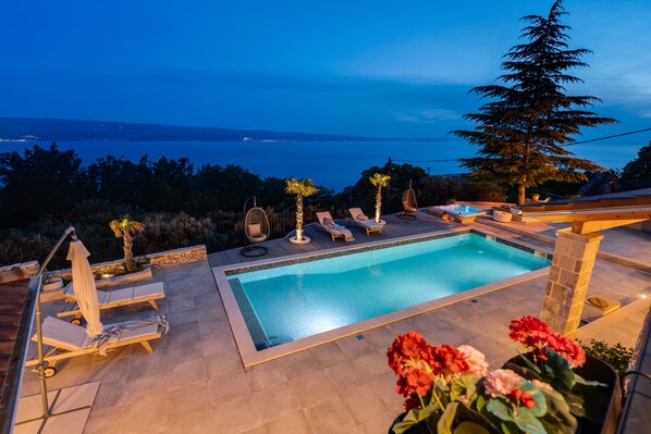 Area piscina con sedie a sdraio e vista sul mare.
