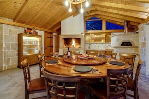Zona pranzo rustica con tavolo e sedie in legno, camino in pietra e forno in pietra.