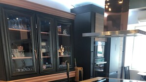 A kitchen with a central island, dark cabinetry, and a stainless steel range hood. - Maison de Village Située Dans un Hameau Très Calme , Agréable à Vivre (saint julien du serre)