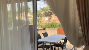 A room with a sliding glass door leading to an outdoor patio area with a table and chairs. - Maison de Village Située Dans un Hameau Très Calme , Agréable à Vivre (saint julien du serre)