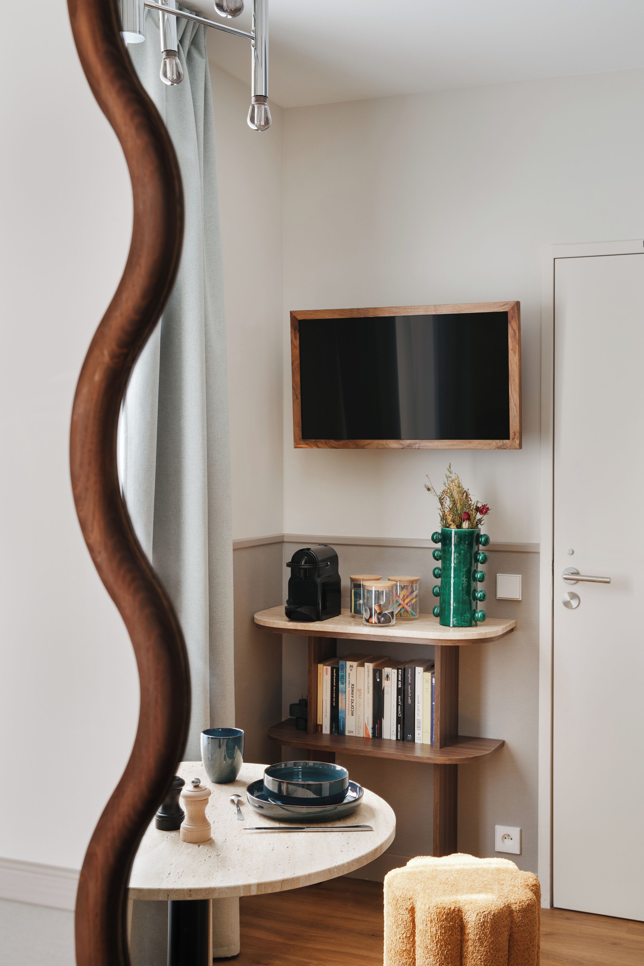 A room with a round table, a bookshelf, a television, and a mirror.