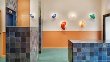 Un hall d’entrée avec un sol carrelé, un comptoir d’accueil et un mur orné d’œuvres d’art abstraites.