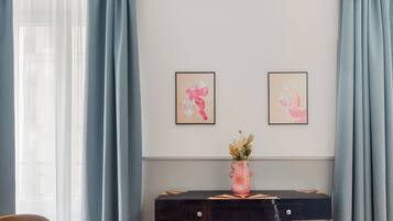 A modern room with a wooden dining table, chairs, a black console table with a vase, and artwork on the wall.