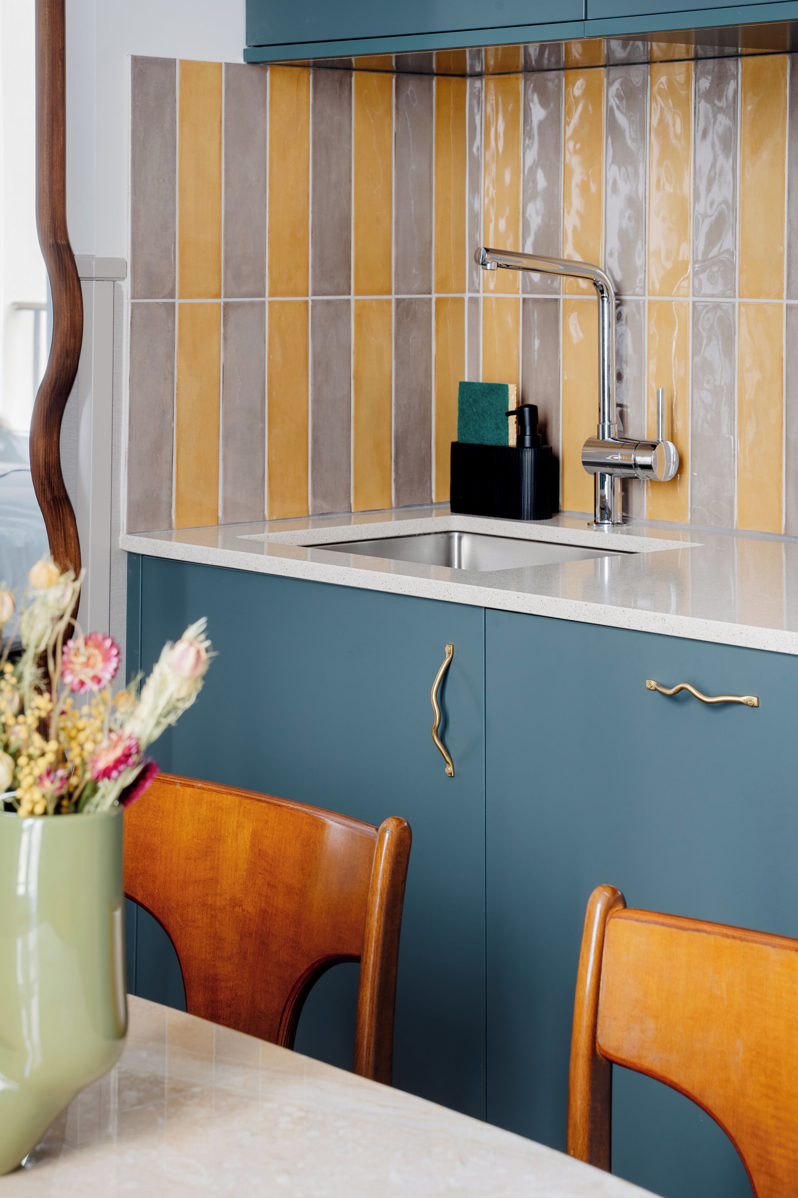 Una cocina con armarios color turquesa, encimera blanca y salpicadero de azulejos.