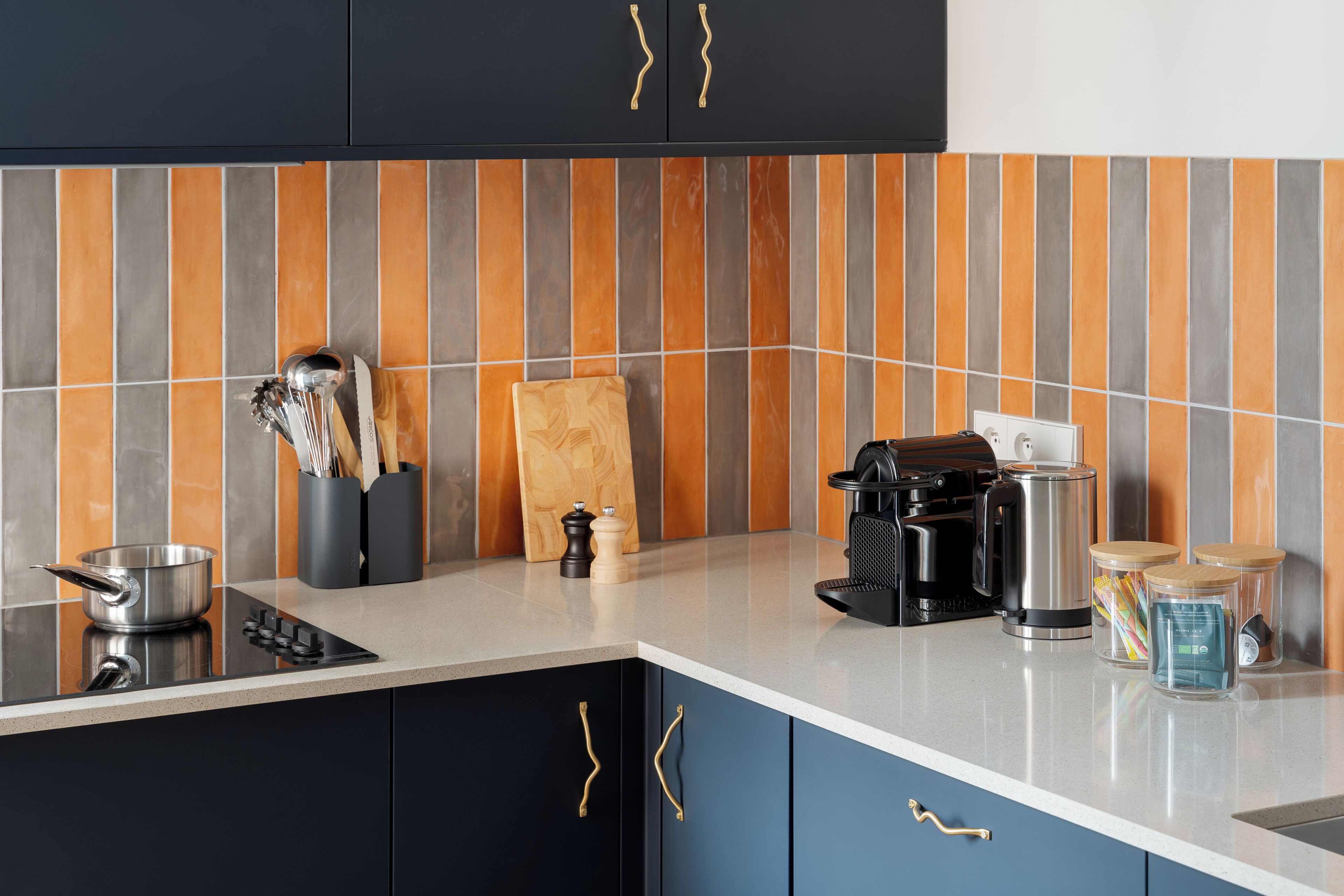 A modern kitchen with a black and blue color scheme, a striped backsplash, and various appliances and utensils.