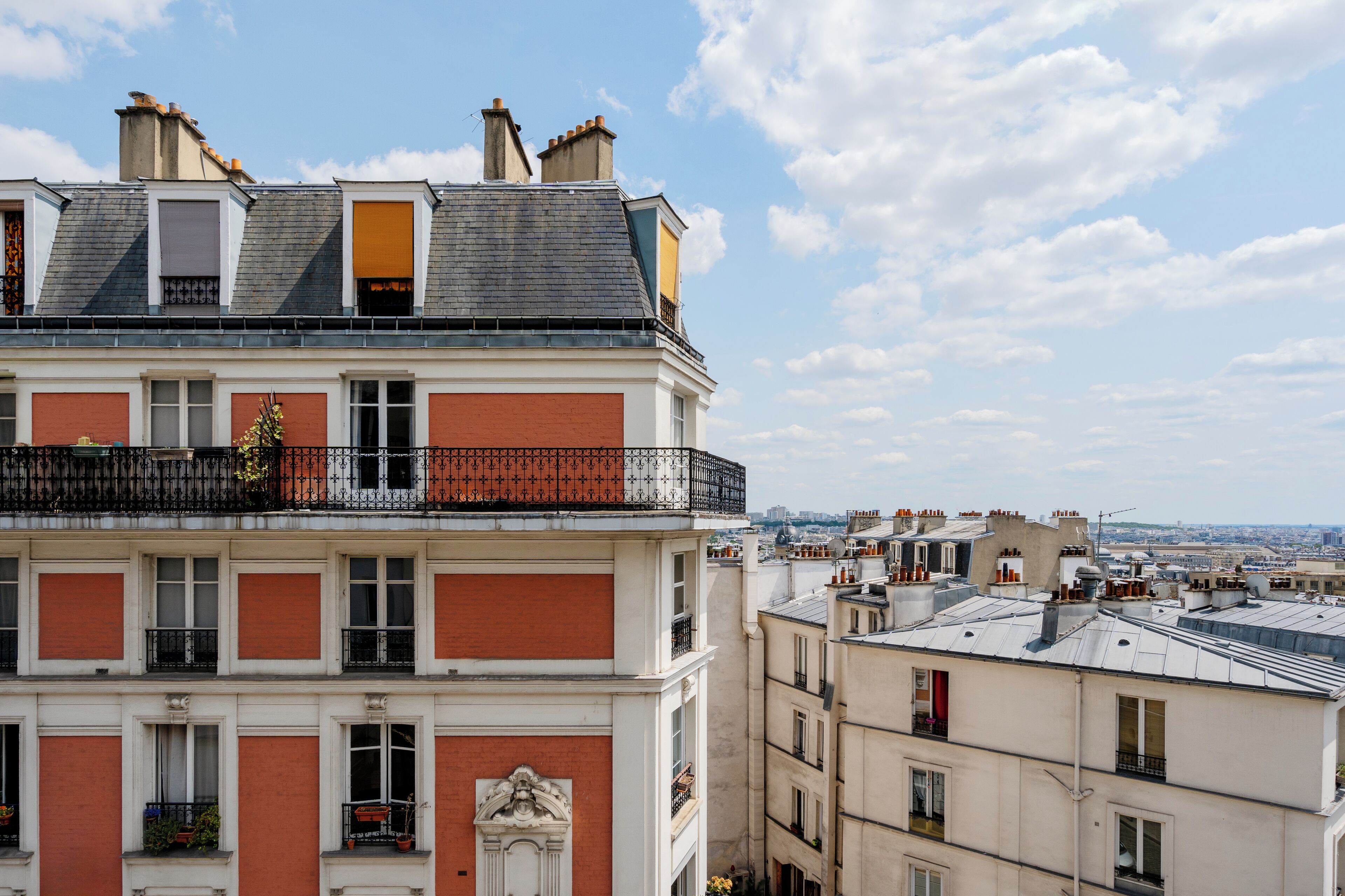 Un immeuble à plusieurs étages, doté d’une façade rouge et blanche, de nombreux balcons et offrant une vue sur le paysage urbain.
