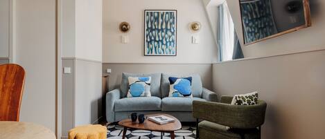 A modern living room with a grey sofa, a small round coffee table, and a patterned rug.