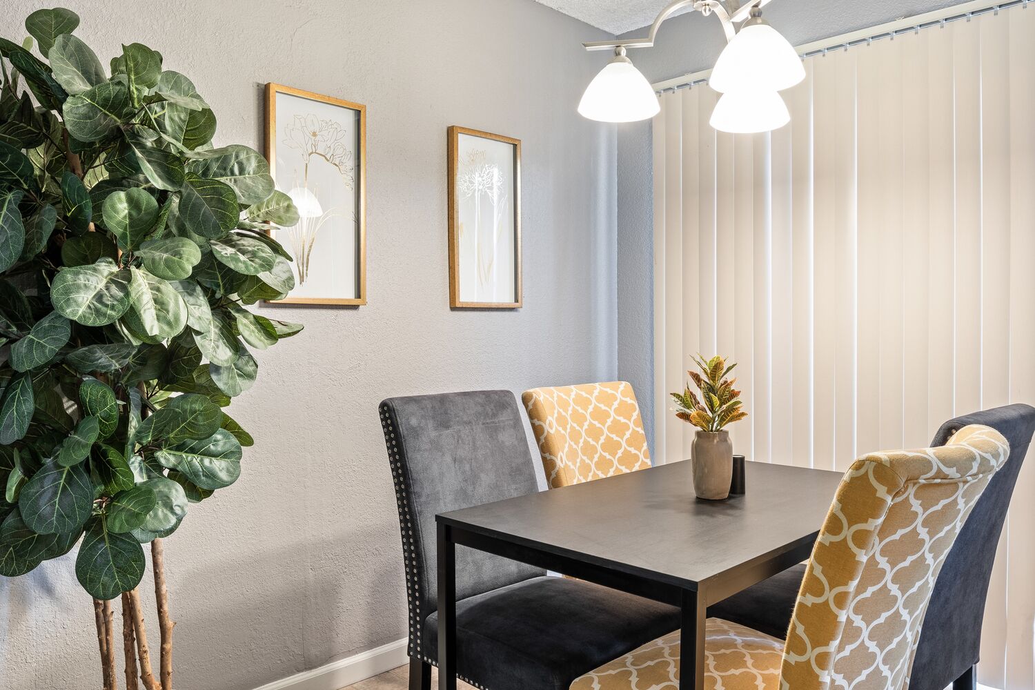 A dining area with a table, chairs, and a potted plant.