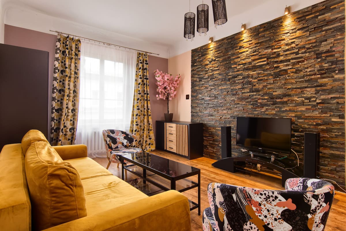 Ein Wohnzimmer mit einer Couch, einem Couchtisch, einem Fernseher und einer Steinwand.