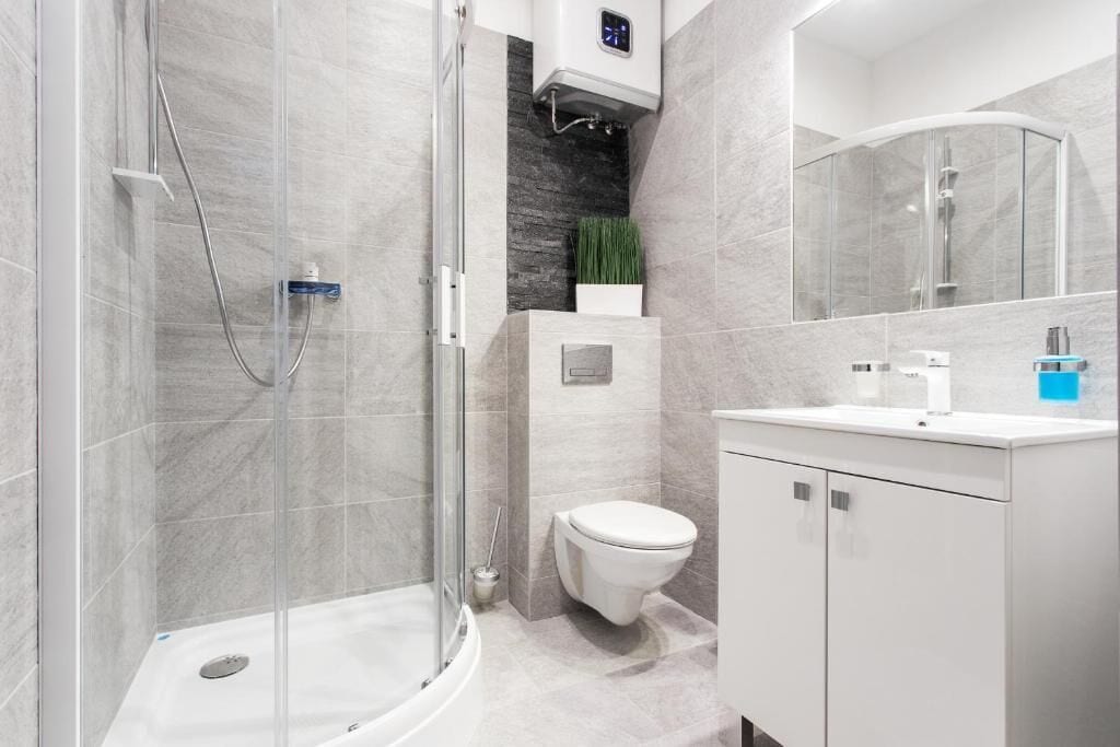A modern bathroom with a glass-enclosed shower, a toilet, and a vanity with a mirror.